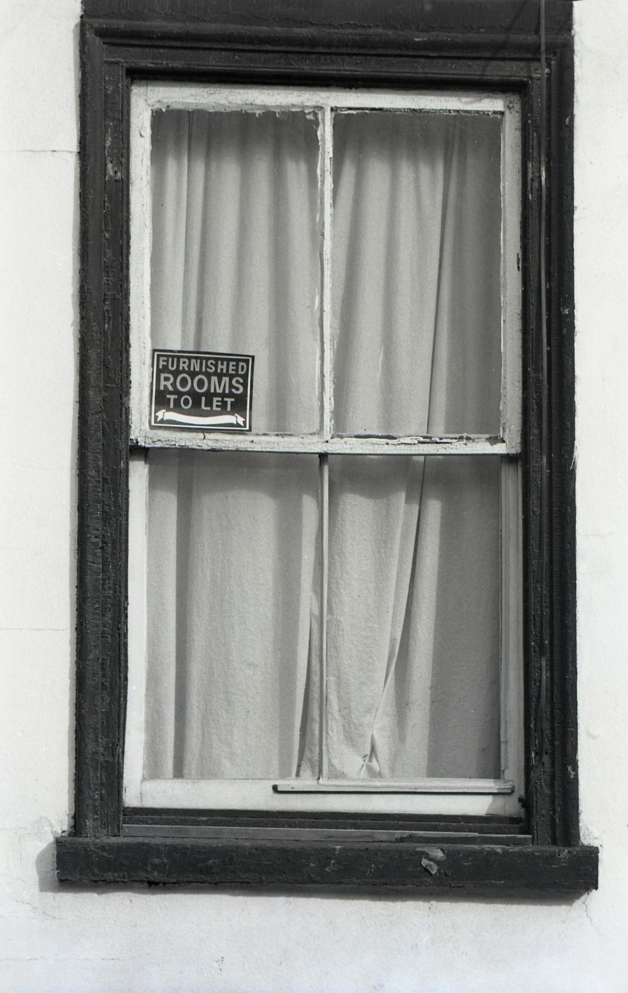 A classic black and white window with a 'Furnished Rooms to Let' sign.